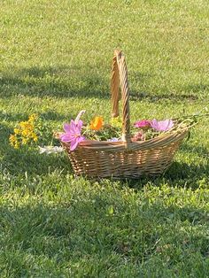 a basket with flowers in it sitting on the grass