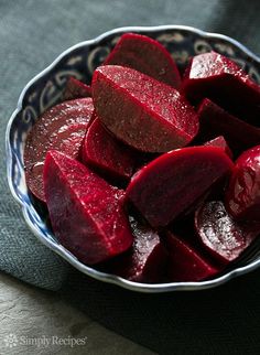 a bowl filled with sliced beets on top of a blue and white table cloth