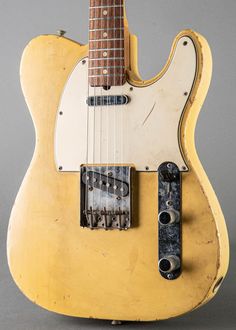 an old yellow electric guitar sitting on top of a table