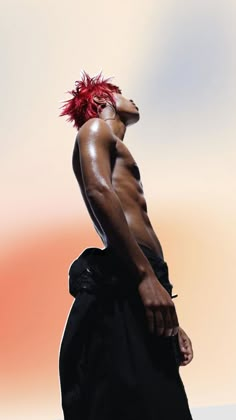 a man with red hair standing in front of a white background wearing a black dress