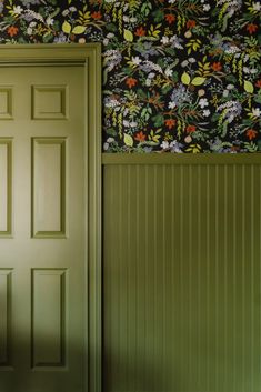 an open door in front of a green wall with floral wallpaper on the walls