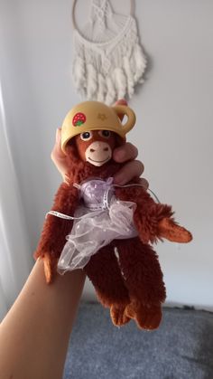 a hand holding a stuffed animal wearing a hat