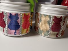 two white jars with colorful designs on them sitting on a table next to each other