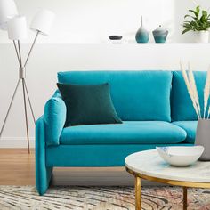 a living room with a blue couch and coffee table in front of a white wall