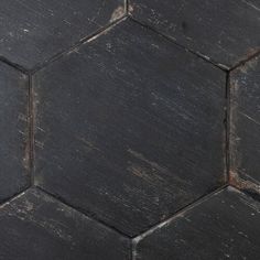 an old black hexagonal tile floor with peeling paint on the top and bottom