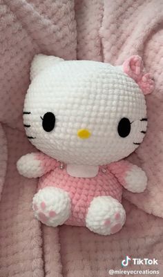 a hello kitty stuffed animal laying on top of a pink blanket