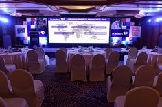 a large conference room set up with white tables and chairs for people to sit at