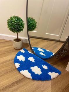 a blue rug with white clouds on it next to a mirror and potted plant