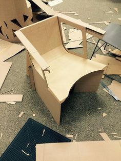 a chair made out of cardboard sitting on the floor next to other pieces of cardboard