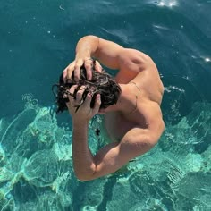 a shirtless man in the water with his hands on his head