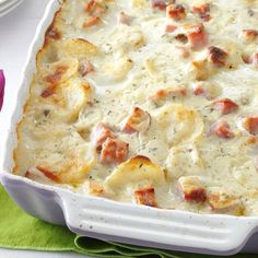 a casserole dish with meat and cheese in it on a green napkin next to a purple flower