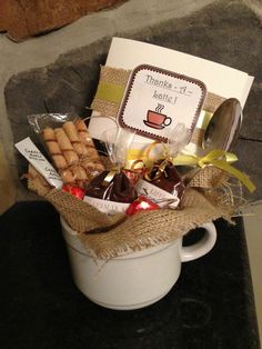 a coffee mug filled with cookies and treats next to a thank you note on a card