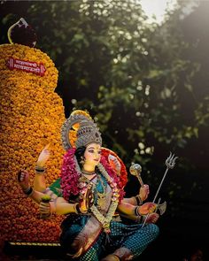 a statue of the hindu god ganesh in front of a flower display at a temple