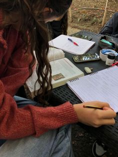 two people sitting at a table with notebooks and pens in their hands, writing on paper