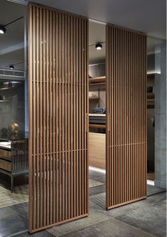 an open wooden door in a room with tile flooring and walls that have vertical slats on them