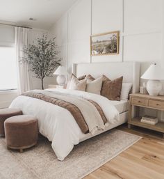 a bedroom with white walls and wood flooring has a large bed in the center