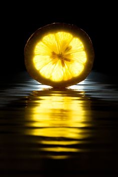 a slice of lemon sitting in the middle of water with its reflection on the surface