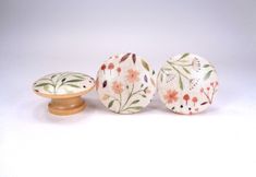 three ceramic knobs with floral designs on them sitting next to each other in front of a white background