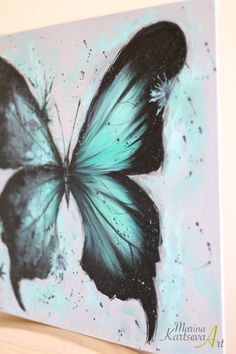 a painting of a blue butterfly on a white background with black and green paint splatters