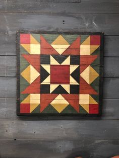 a wooden wall hanging on the side of a building with an old fashioned patchwork pattern