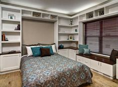 a bed sitting in a bedroom next to a window covered in blue and white pillows