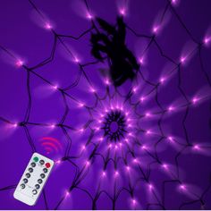 a remote control sitting on top of a spiderweave net with purple lights around it