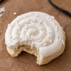 a cookie with white frosting is on a piece of brown paper