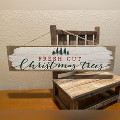 a wooden sign that says fresh out christmas trees sitting on top of a table next to a chair