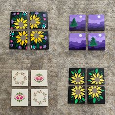 four square coasters with painted flowers and trees on them sitting on the ground next to each other