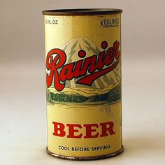 an old beer can with mountains in the background and red lettering on it that says rainier