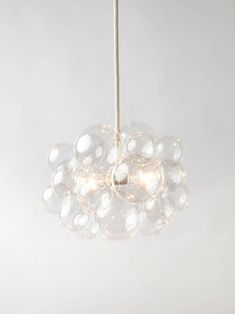 a cluster of bubbles hanging from a ceiling light in a room with white walls and flooring