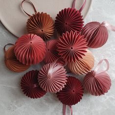 paper fans are arranged on a plate with pink ribbons and bowes hanging from them