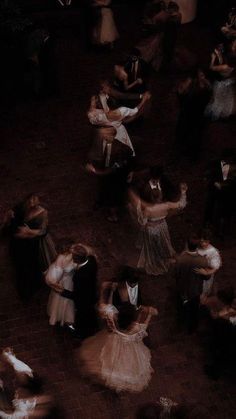 a group of people standing around each other on top of a dance floor with their arms in the air