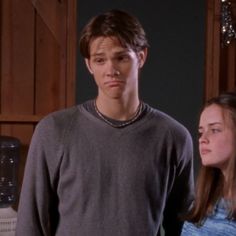 a young man standing next to a woman in a kitchen