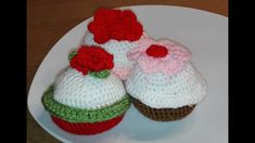 two crocheted cupcakes are sitting on a white plate with strawberries