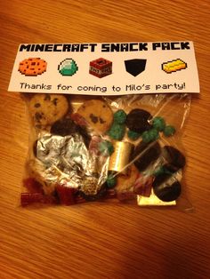 a bag filled with lots of cookies on top of a wooden table next to a sign that says minecraft snack pack