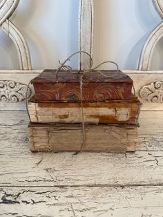 an old book tied to a rope on top of two other books in front of a mirror