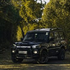 a black suv driving down a dirt road next to trees and bushes with the words scorpion written on it