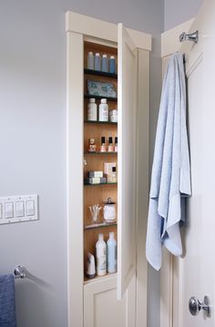 a towel hanging on the wall next to a shelf filled with bottles and soaps