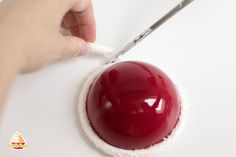 a person using a needle to trim a red object