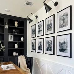 black and white photographs hang on the wall above a wooden table