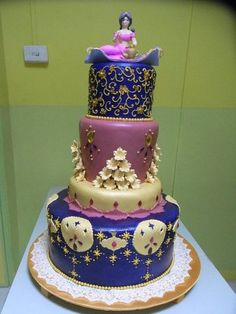 a three tiered cake is decorated with gold and purple designs on it's sides