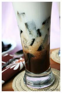 a tall glass filled with ice cream and chocolate syrup on top of a place mat