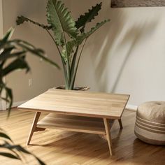 a wooden coffee table sitting on top of a hard wood floor next to a potted plant