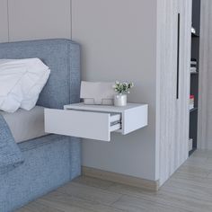 a bed with a blue headboard and white pillows next to a wall mounted cabinet