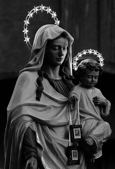 a statue of the virgin mary holding a child in her arms with lights around her head