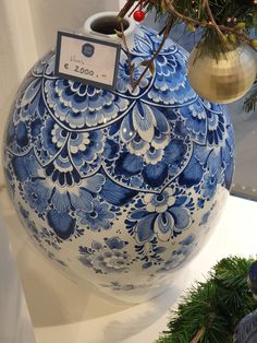 a blue and white vase sitting on top of a table next to a christmas tree