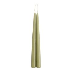 two green candles sitting next to each other on a white surface with one candle in the middle