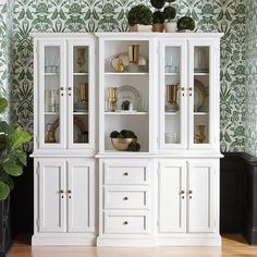 a white china cabinet with glass doors and gold trimmings in a living room