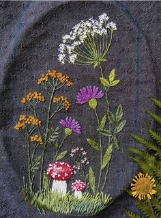 a close up of a piece of cloth with flowers and plants embroidered on the side